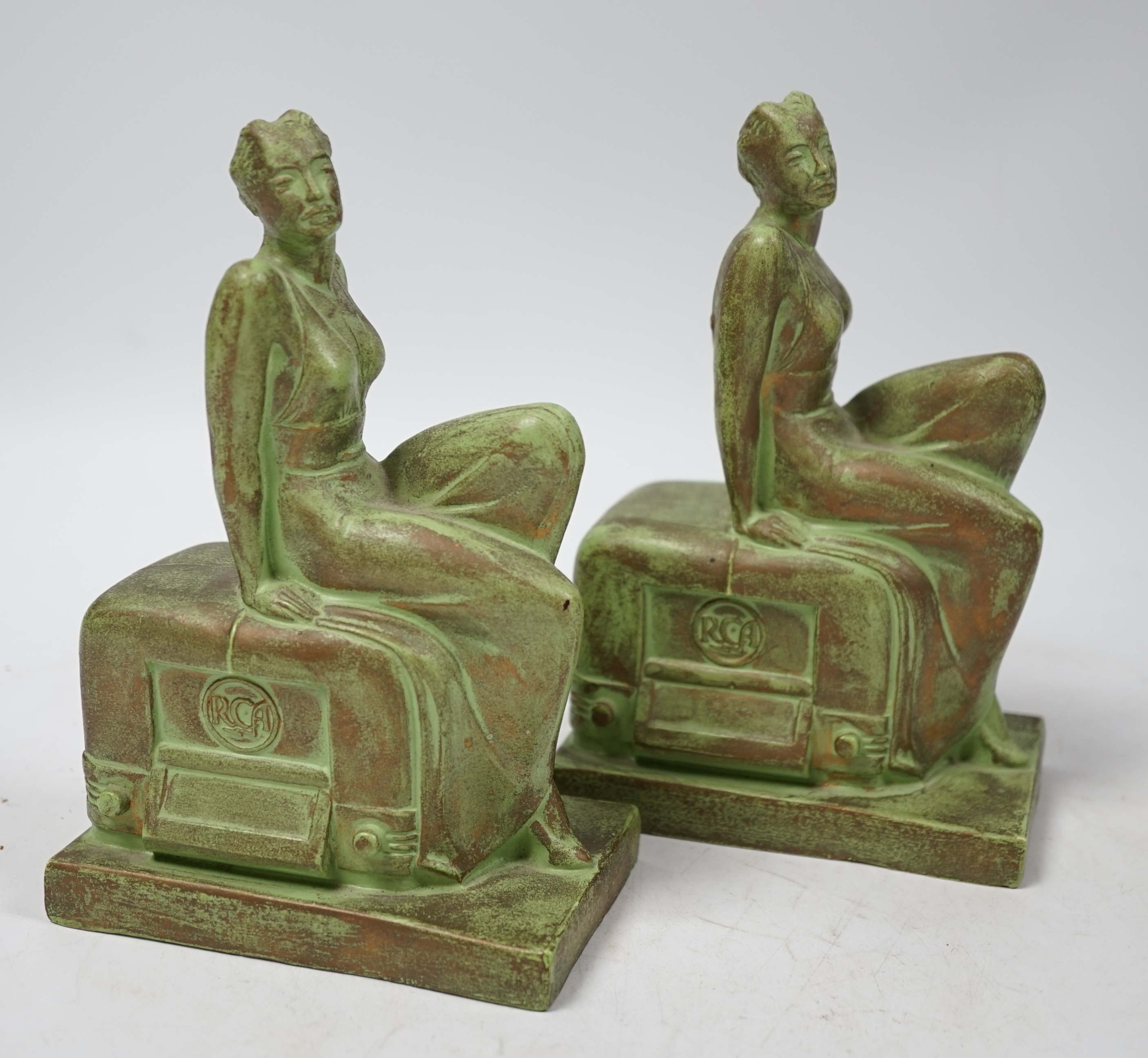 A pair of Art Deco RCA Victor bronzed ceramic ‘chalkwear’ bookends, in the form of a woman sitting on a 1930s radio, produced for the 1939 New York World Fair to promote the RCA Victor record label, 17cm high
